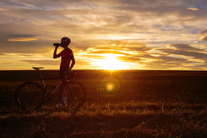 A cyclist taking a drink at sunset