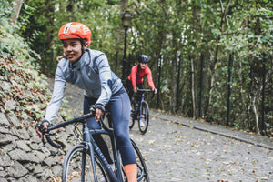 Woman biking on a road in a cobblestone trail in a wooded area