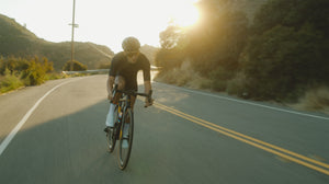 Man cycling around the bend on a hillside road
