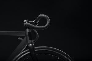 Handlebars and front part of a black bike frame against a black background