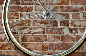 Close-up of a commuter bike wheel against a brick wall