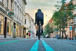 View from behind of a man cycling down the center line on a city street