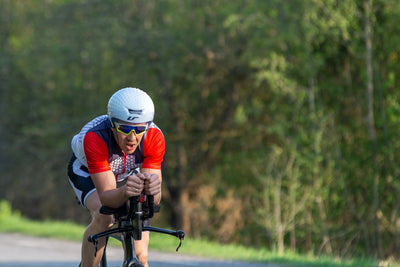 Road cyclist leaning forward and pedaling hard on a tree-lined road