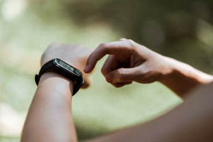 Close-up of a woman’s arms with one hand pointed at the heart rate monitor on her other wrist.