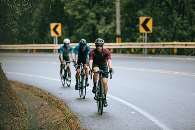 Three men cycling around a bend in the road