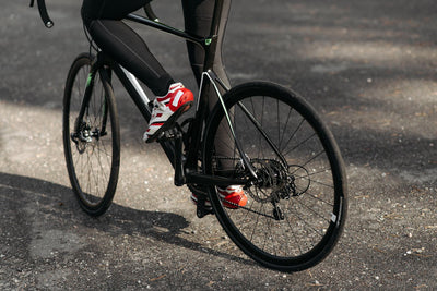 Legs of cyclist pedaling on a black road bike