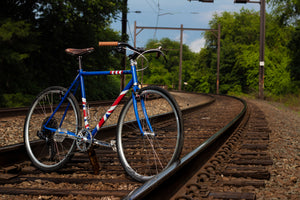 Custom-made roaster bicycle with Union Jack and US flag stripes on railroad tracks