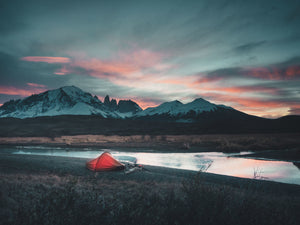 Bikepacker's tent set by a lake with mountains in the background