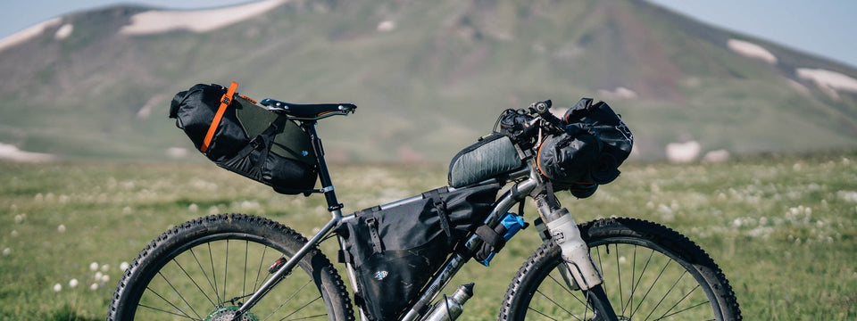Bike in front of mountains loaded with panniers and gear for a bikepacking trip, equipped with a Selle Anatomica leather saddle