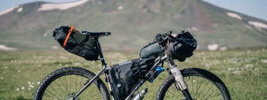 Mountain bike with bags and leather saddle in front of a hill