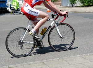 Lower body of cyclist pedaling a road bike on pavement