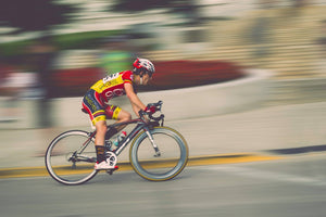 Man racing his bicycle by quickly against a blurred background