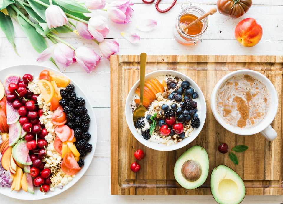 Breakfast setting with granola, fruits, avocados, honey and a latte