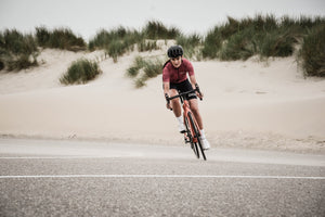 Woman cycling on a road by a beach on an overcast day