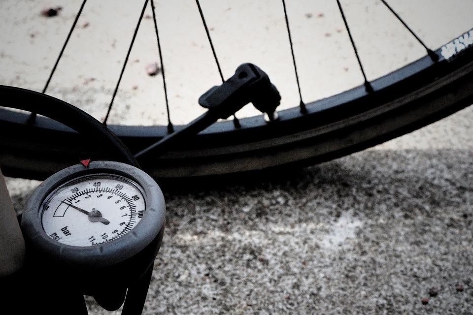 Close-up of flat bicycle tire with air pump and pressure gauge attached