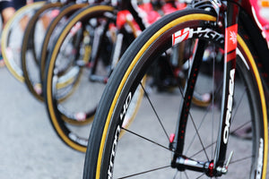 Close-up on front bicycle wheel in a row of road bikes