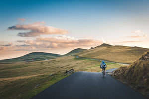 Cyclist biking up a road that winds through hills