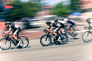 Group of cyclists speeding by on a road against a blurred background