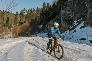 Man cycling uphill on a snowy road in winter