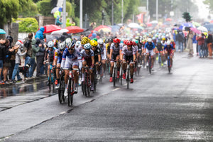 Group of cyclists riding in the rain while spectators watch