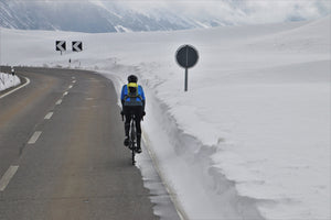 Cyclist riding on a highway in winter through snow-covered mountains