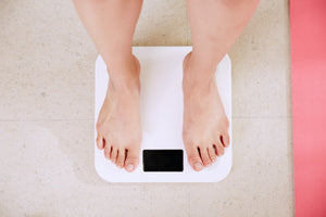 Feet of a woman weighing herself on a white scale