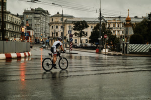 Man cycling through a city intersection on wet roads