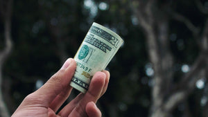 Man’s hand with a roll of $20 bills in his fingertips