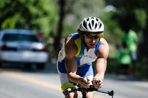 Muscular man grimacing slightly as he leans forward and pedals his road bike