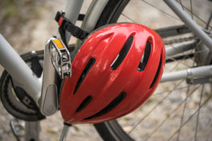 Red bicycle helmet hanging strapped around the crank and pedals on a bike