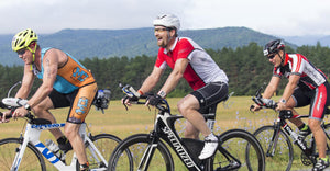 Three road cyclists riding with mountains in the background