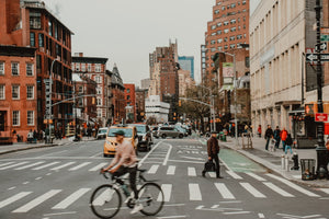 Man riding his bicycle through a busy New York intersection