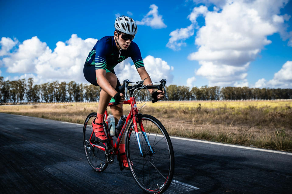 Man riding a red road bike on a two-lane country road
