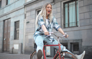 Woman being silly while riding bike with legs outstretched in front of her, not on the pedals