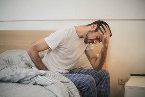 Man sitting up in bed looking distressed because he can’t sleep