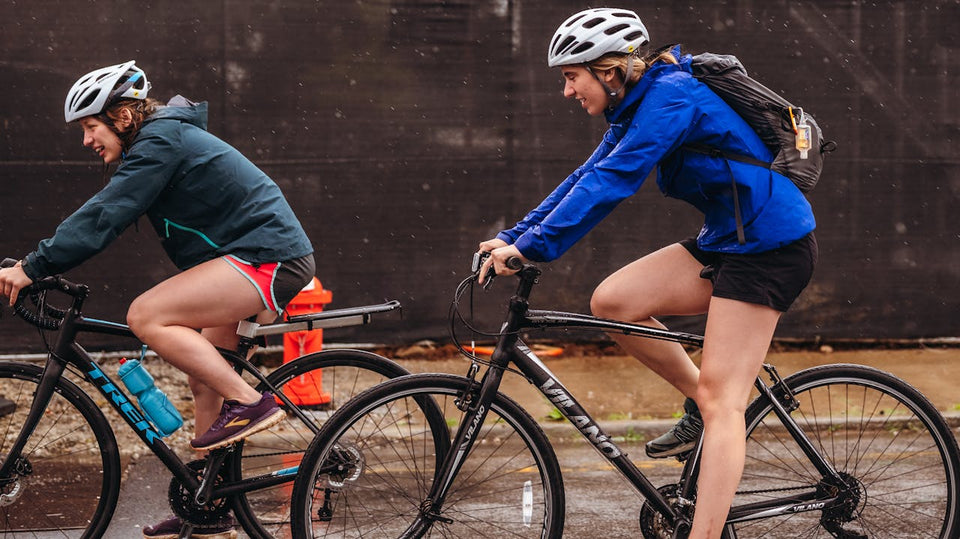 Two women cycling close together on a gloomy looking day