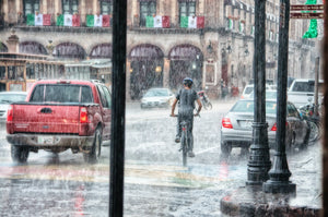 Person riding a bike on a city street in the rain