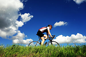 Man cycling below a bright blue sky with a few clouds