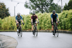 Three men cycling together around a bend in the road