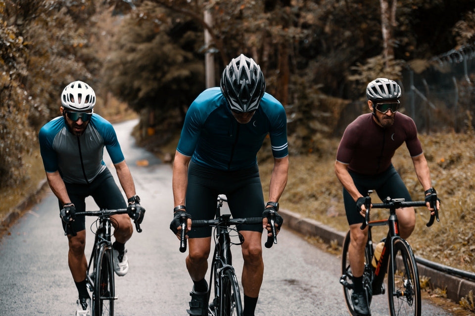 Three men riding together on their bicycles up a hill