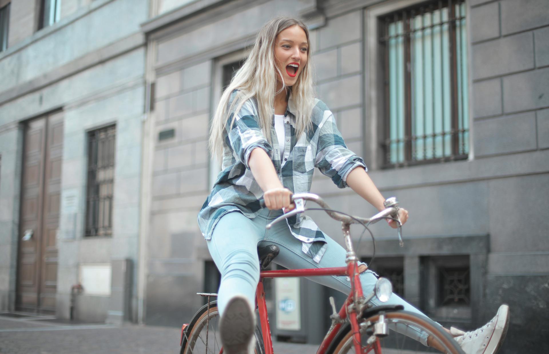Blonde woman riding playfully on a bike with her legs sticking straight out