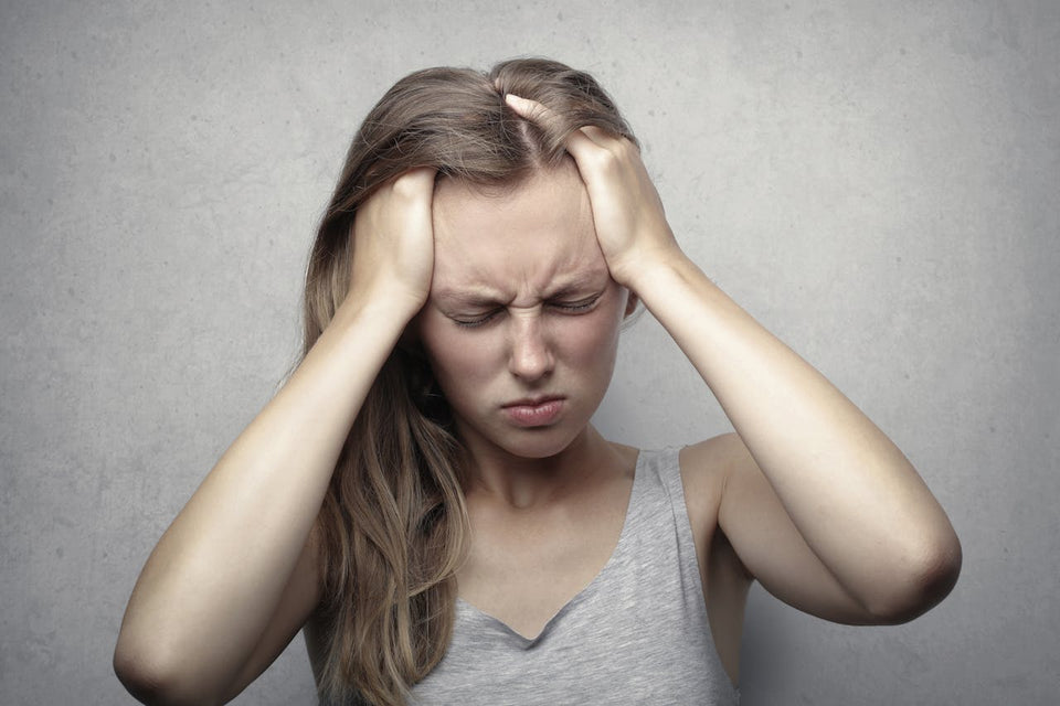 Young woman grabbing her head and grimacing in pain with her eyes shut