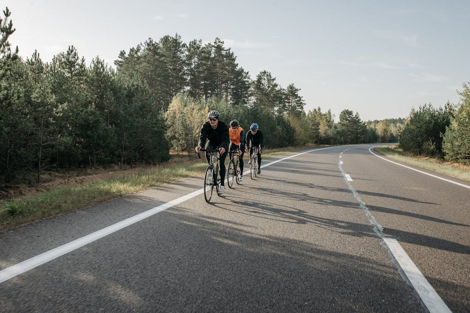 Three distance cylists pedaling in a line on a stretch of open road