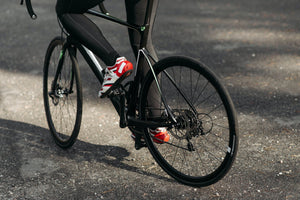 Legs of a cyclist pedaling a black road bike