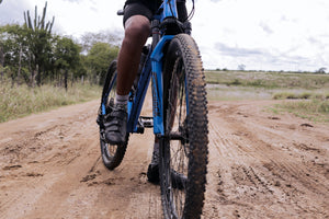 Close-up view of the front tire on a mountain bike with a rider standing over it on a dirt trail