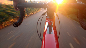 Rider’s view over the handlebars on a bicycle descending quickly down a hill toward sunset