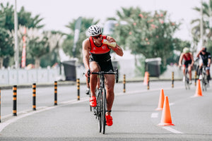 Strong cyclist riding bicycle on asphalt street and drinking from a water bottle