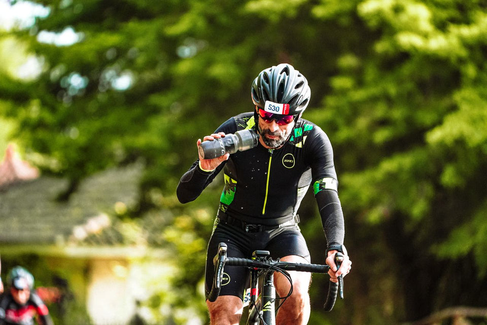 Cyclist drinking water while biking through scenic outdoor park