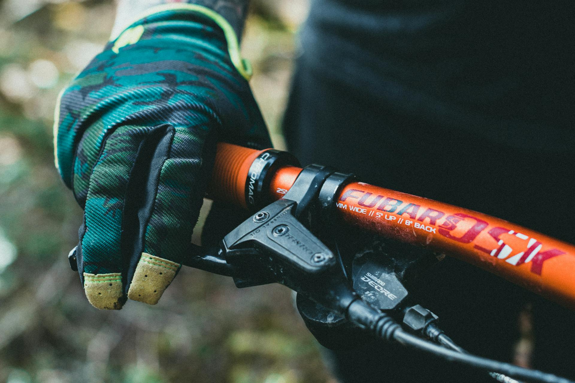 Cyclist's gloved hand wrapped around a handlebar grip and brake