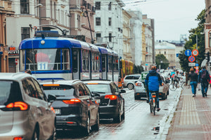 Man cycling on a busy street alongside a line of cars